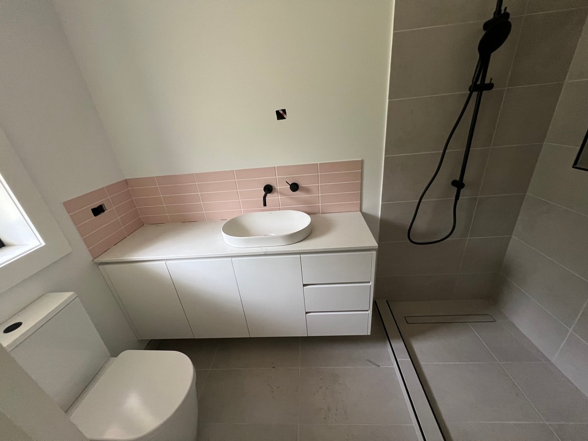 Vanity area with blush pink subway tile splashback, vessel sink and matte black tapware — Cranbourne South by Casey Quality Coatings